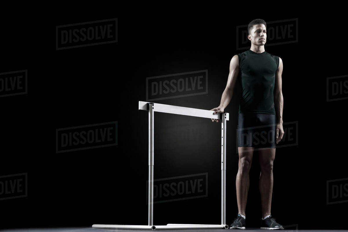 Male athlete standing by hurdle Stock Photo Dissolve