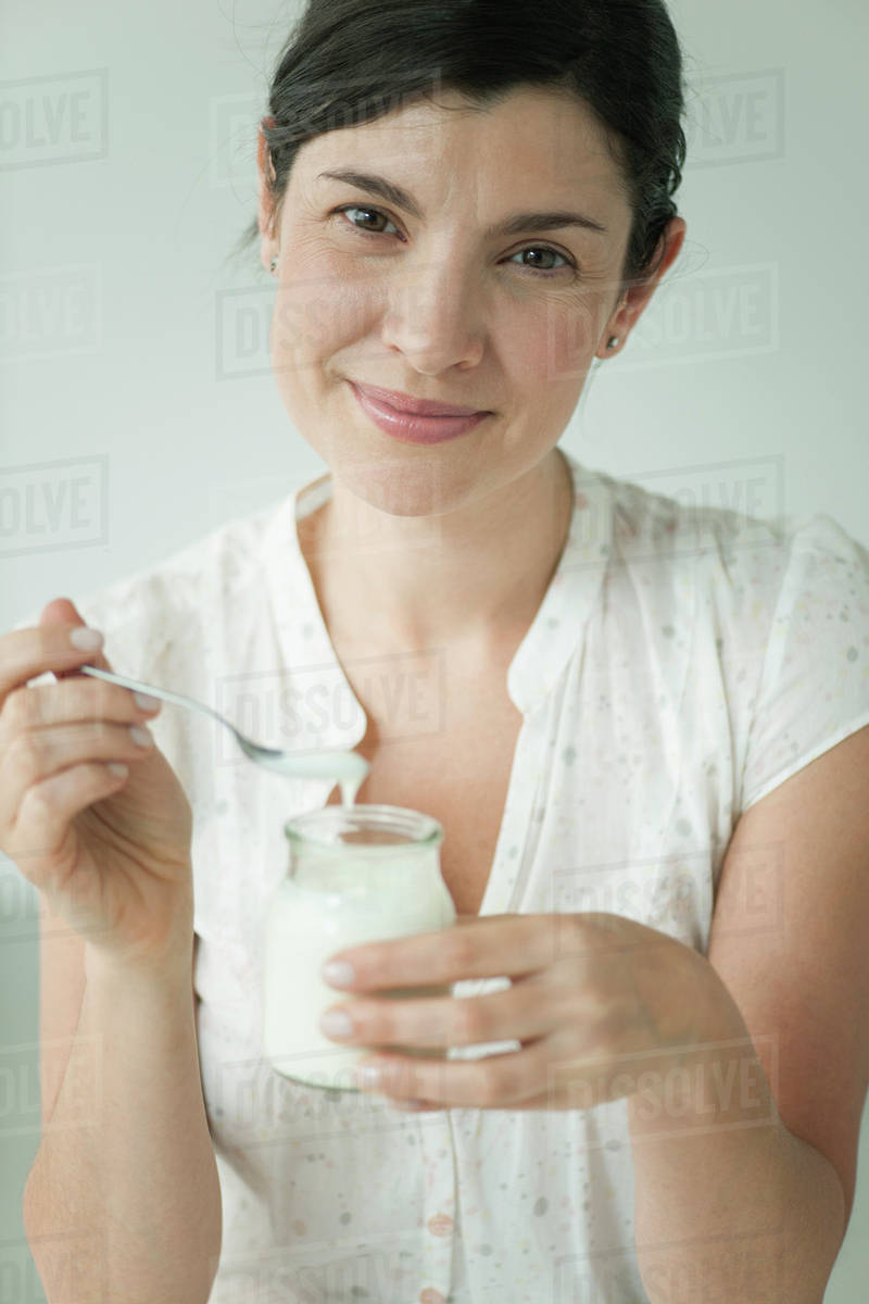 Woman eating yogurt, portrait Stock Photo Dissolve