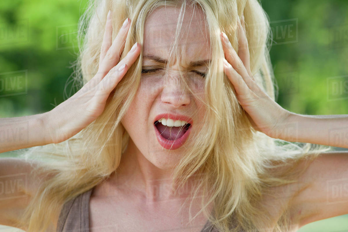Woman with head in hands, screaming Stock Photo Dissolve
