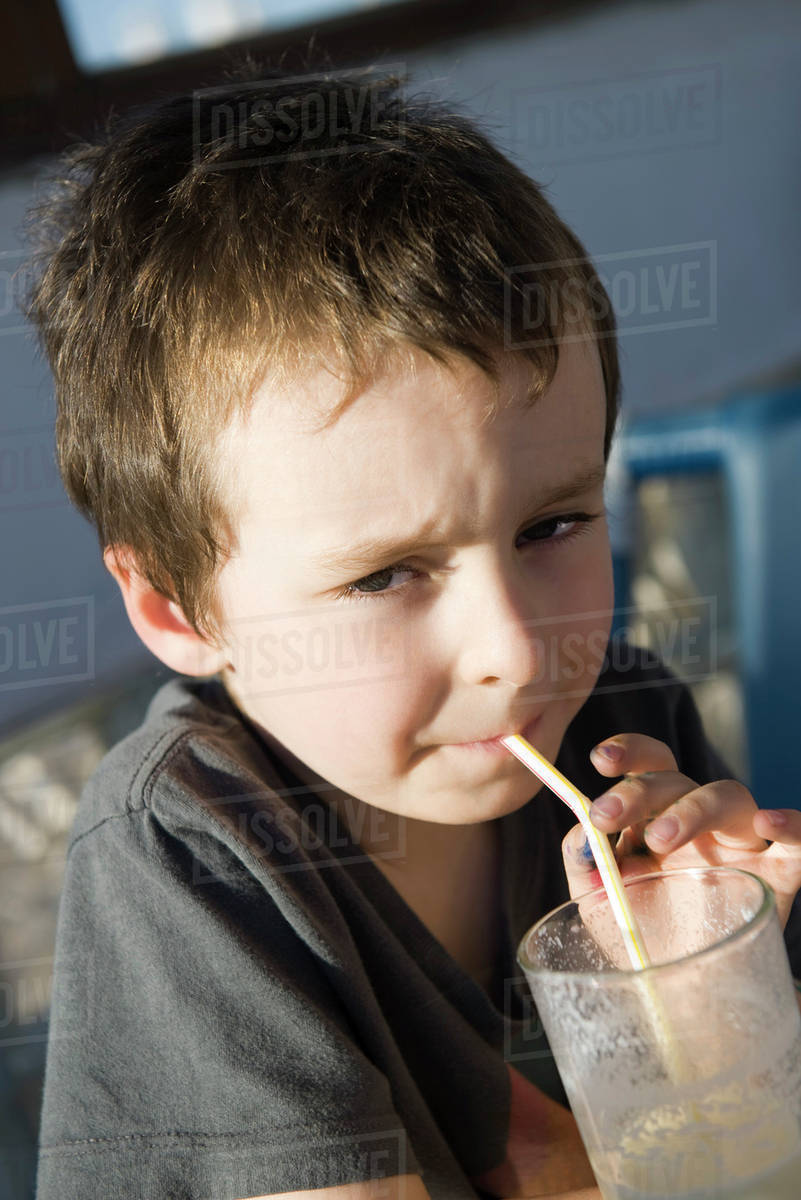 Boy drinking through straw, portrait Stock Photo Dissolve
