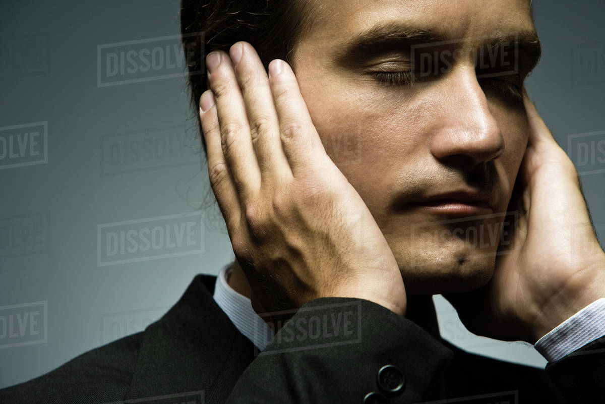 Man with hands held over ears and eyes closed Stock Photo Dissolve