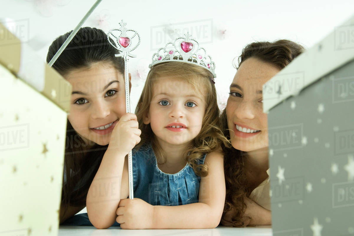 Little girl with mother and sister, dressed as princess, birthday gifts in foreground Royalty-free stock photo