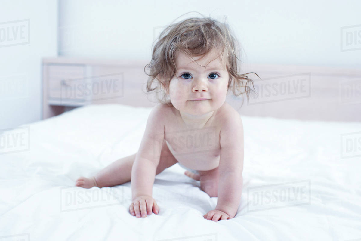 Baby girl crawling on bed Stock Photo Dissolve
