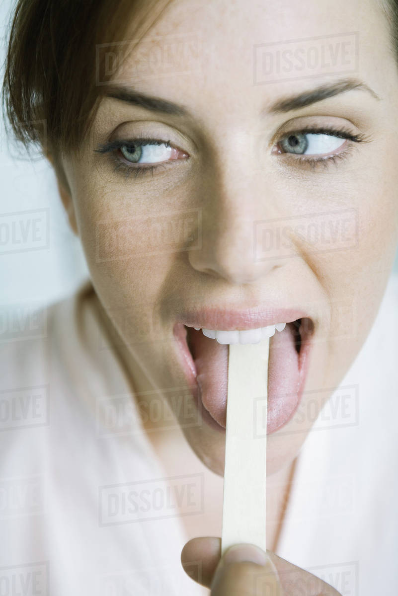 Woman having tongue held down with tongue depressor Stock Photo Dissolve