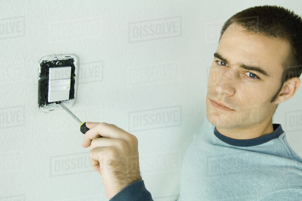 Man removing light switch cover Stock Photo Dissolve