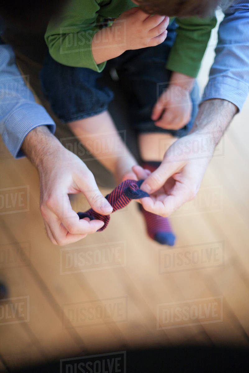 Father helping toddler put on socks, cropped Stock Photo Dissolve