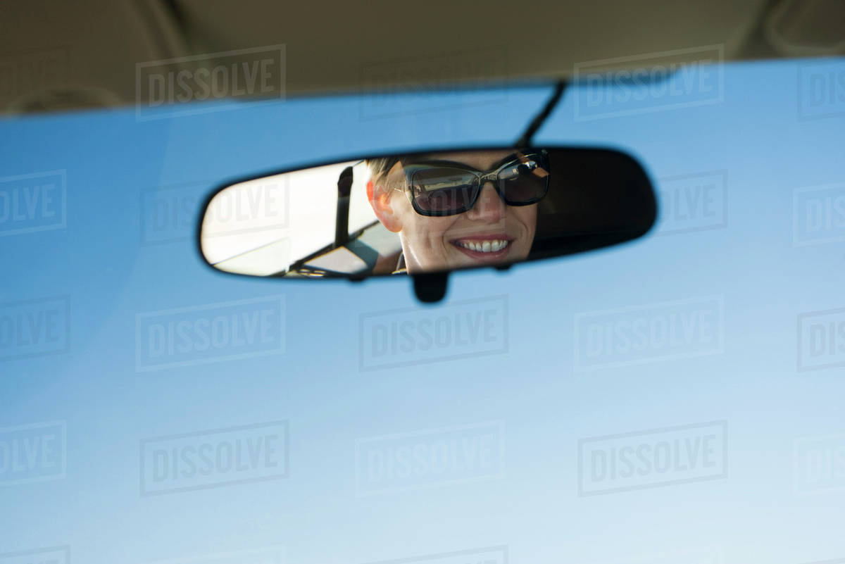 Woman's face reflected in rearview mirror - Stock Photo - Dissolve