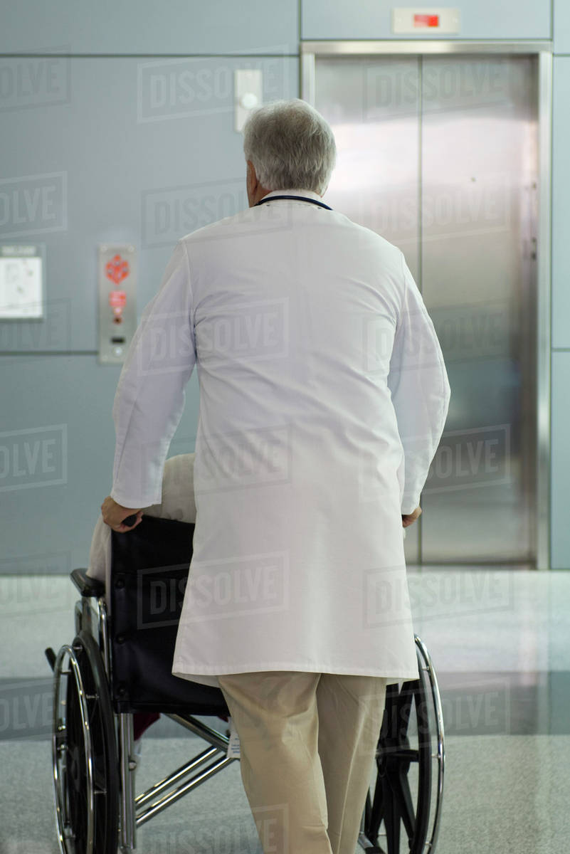 Doctor pushing patient in wheelchair Stock Photo Dissolve