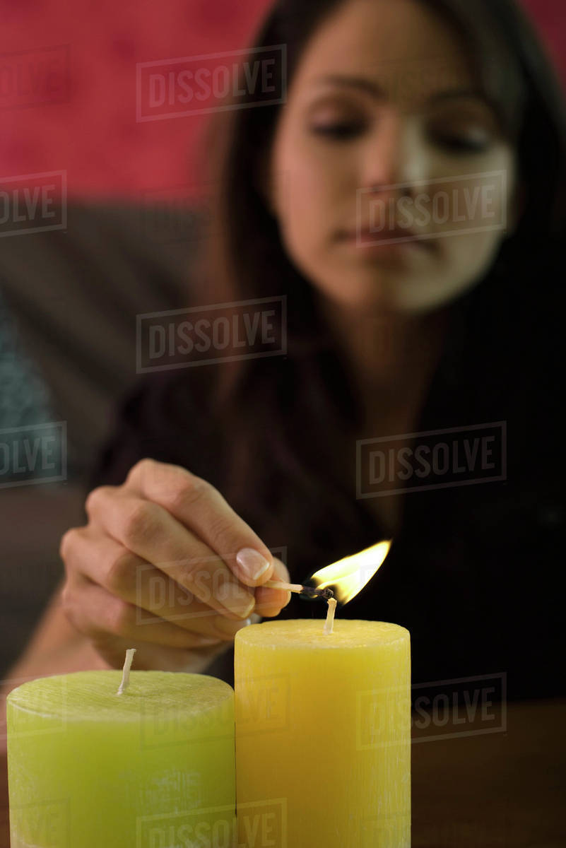Young woman lighting candles, focus on foreground Stock Photo Dissolve