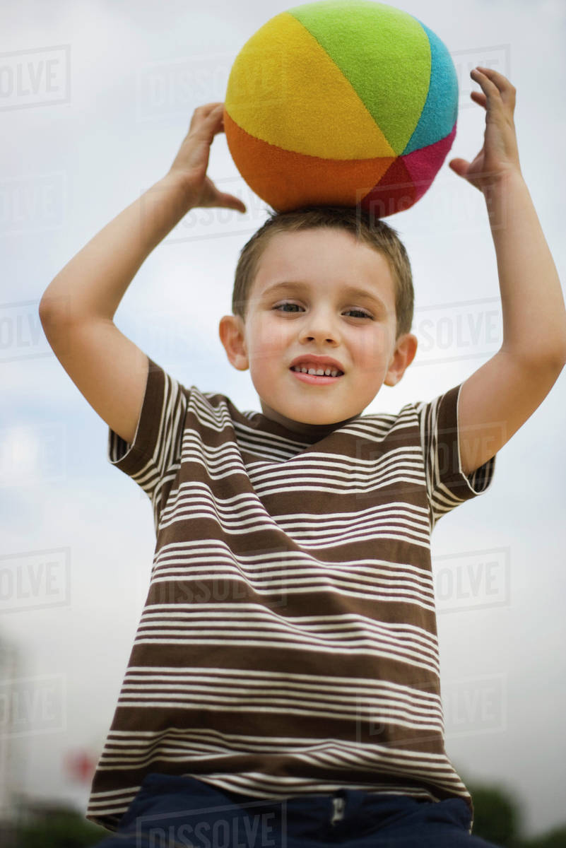 Boy balancing ball on head Stock Photo Dissolve