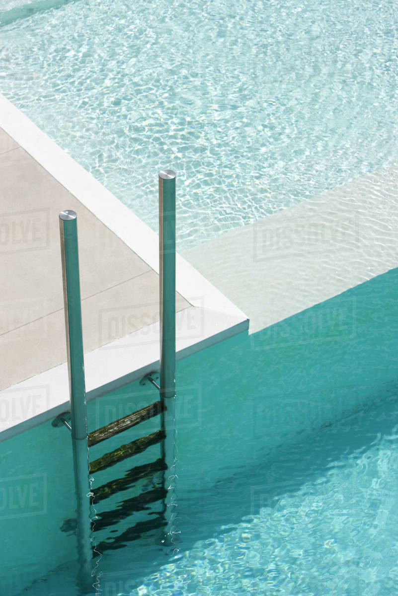 Swimming pool ladder at deep end separated from shallow pool by ledge