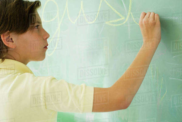 Boy writing in cursive on blackboard - Royalty-free Stock Photo | Dissolve