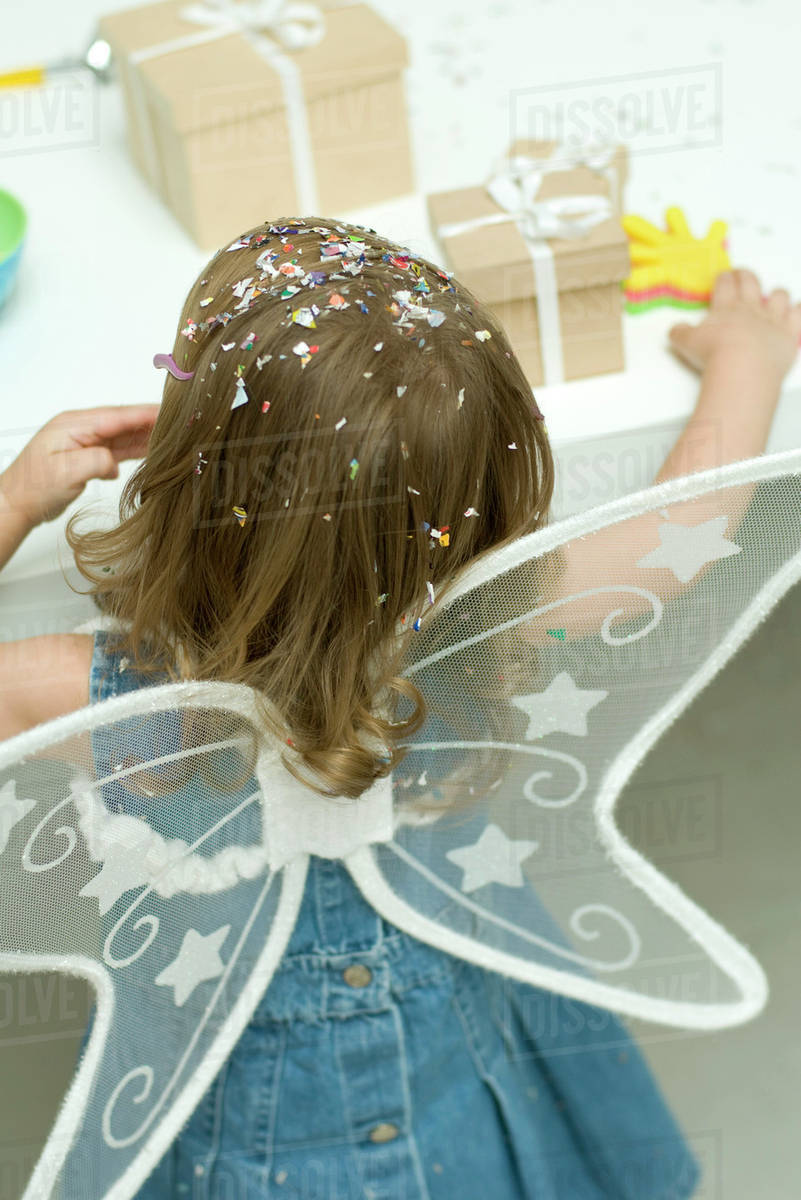 Little girl wearing wings, confetti in her hair, rear view Royalty-free stock photo