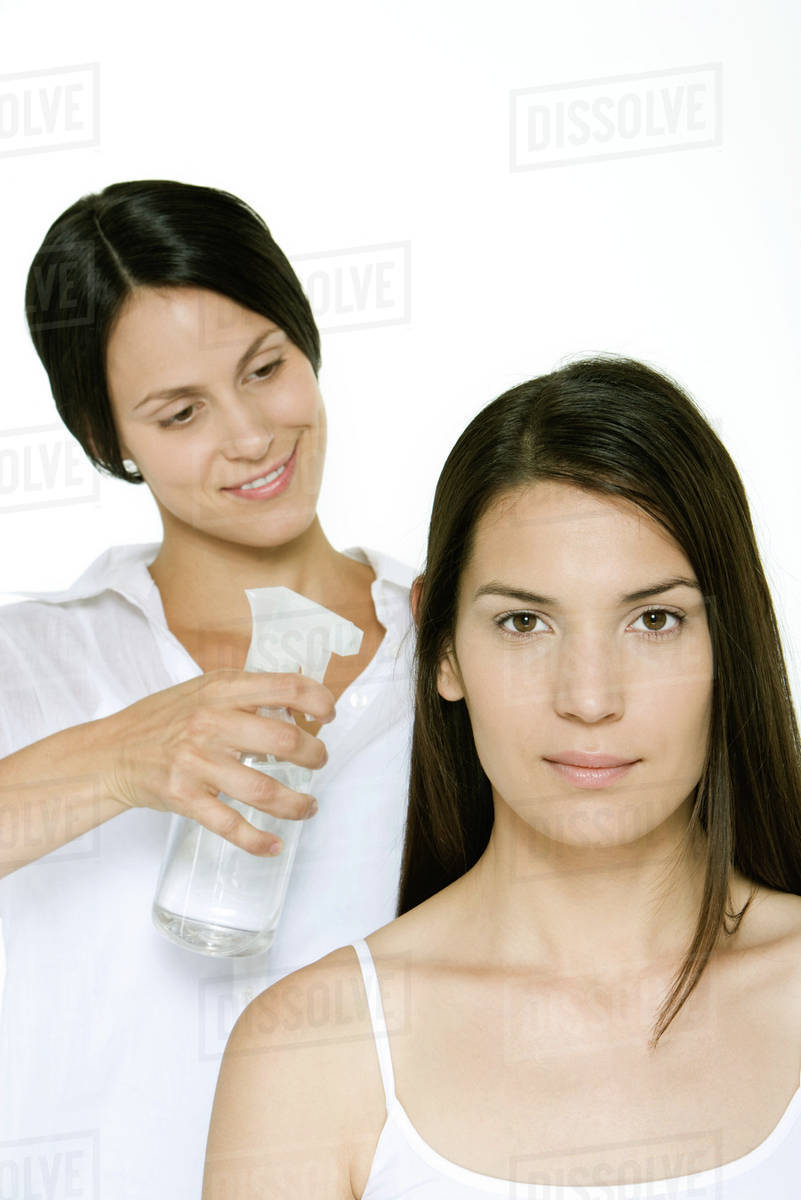 Hair stylist using spray bottle to moisten a woman's hair Stock Photo