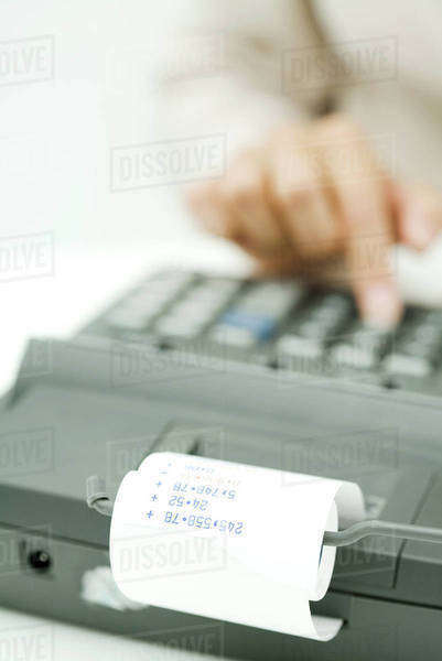 Person using adding machine, cropped view - Stock Photo - Dissolve