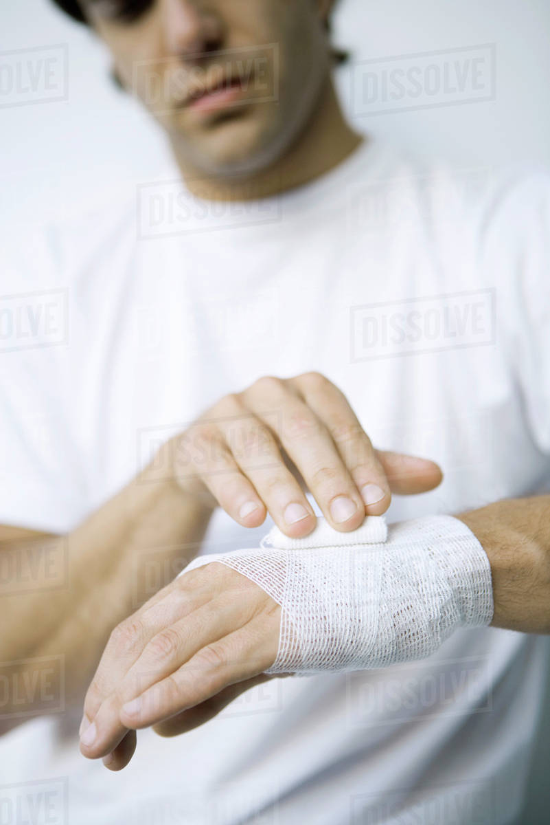 Man wrapping gauze around his wrist and hand, cropped view Stock
