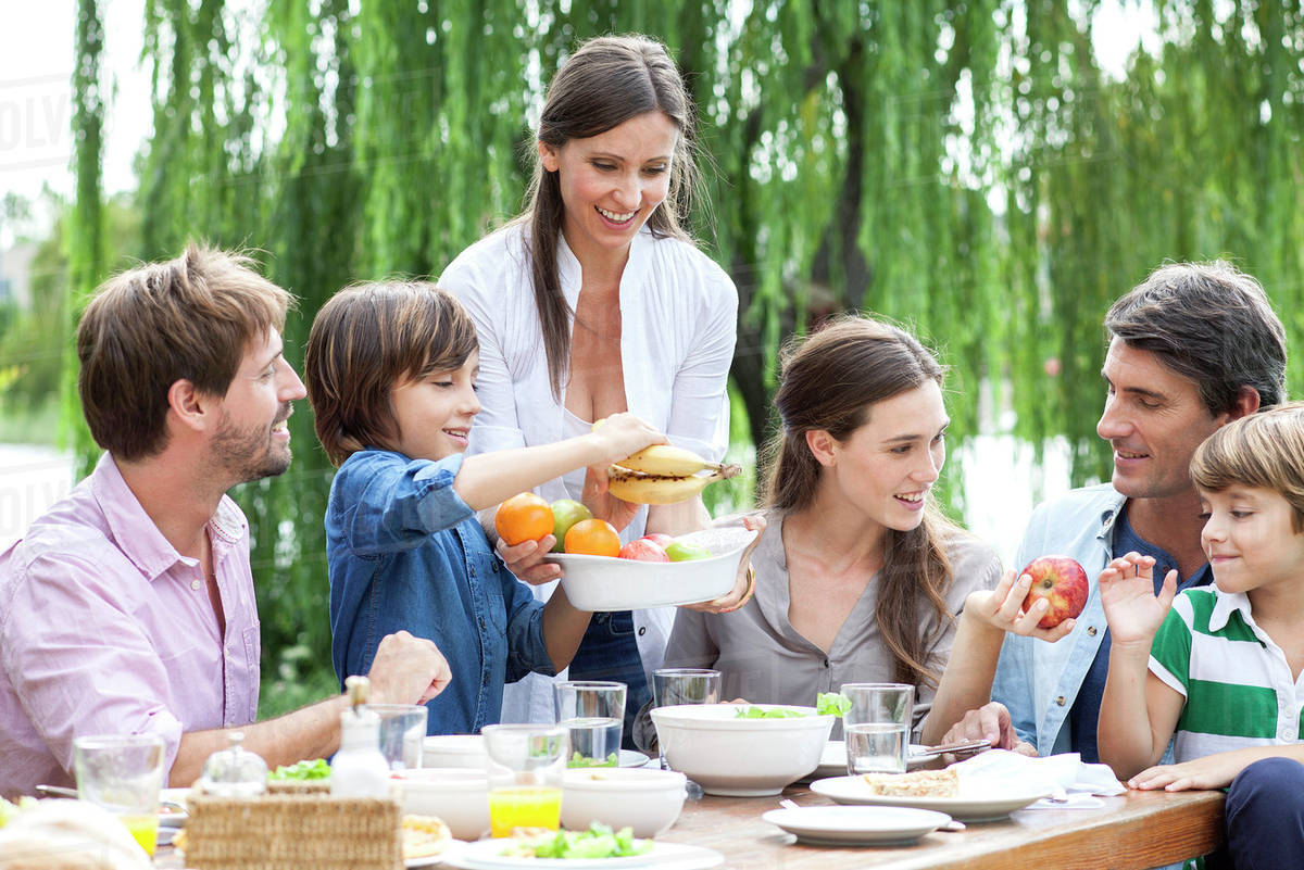 Family eating healthy meal together outdoors - Stock Photo - Dissolve