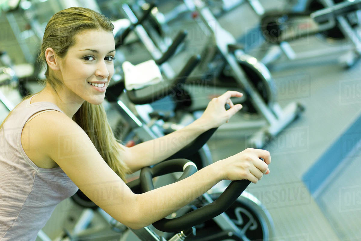 Woman riding exercise bike Stock Photo Dissolve
