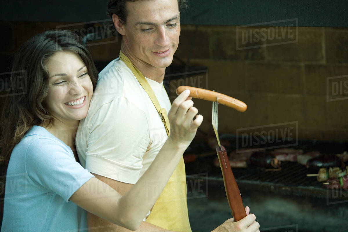 Couple having cookout, woman taking hotdog from man's fork - Royalty ...