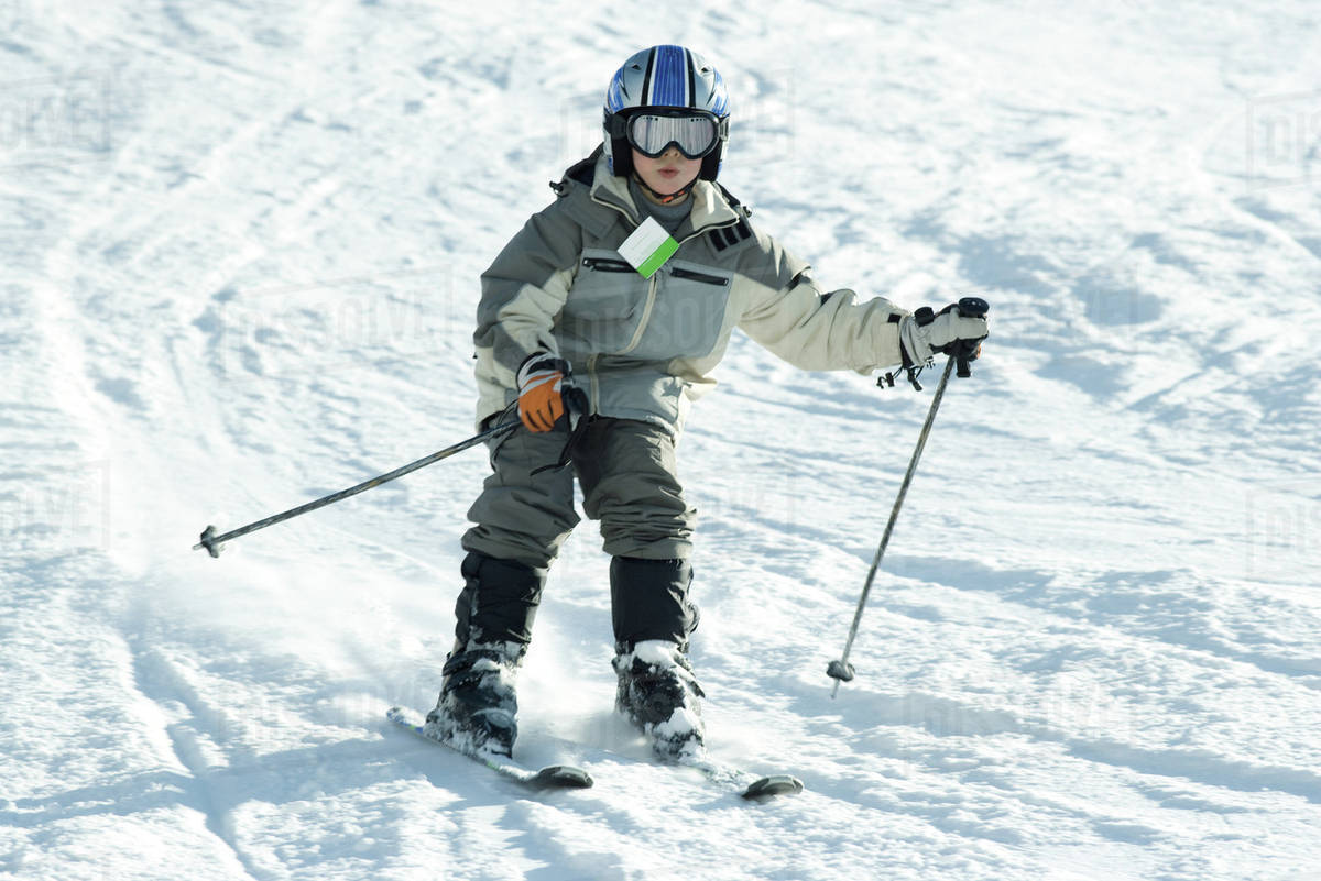 Boy skiing down hill, full length Stock Photo Dissolve