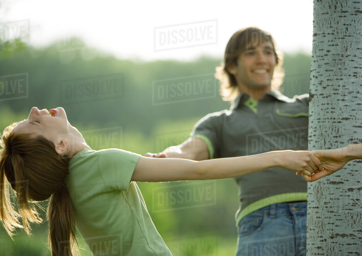 Young people making circle around tree Stock Photo Dissolve