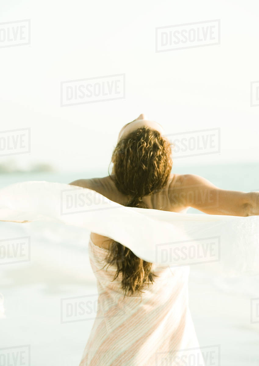 Woman throwing head back and spinning around with scarf in wind Stock