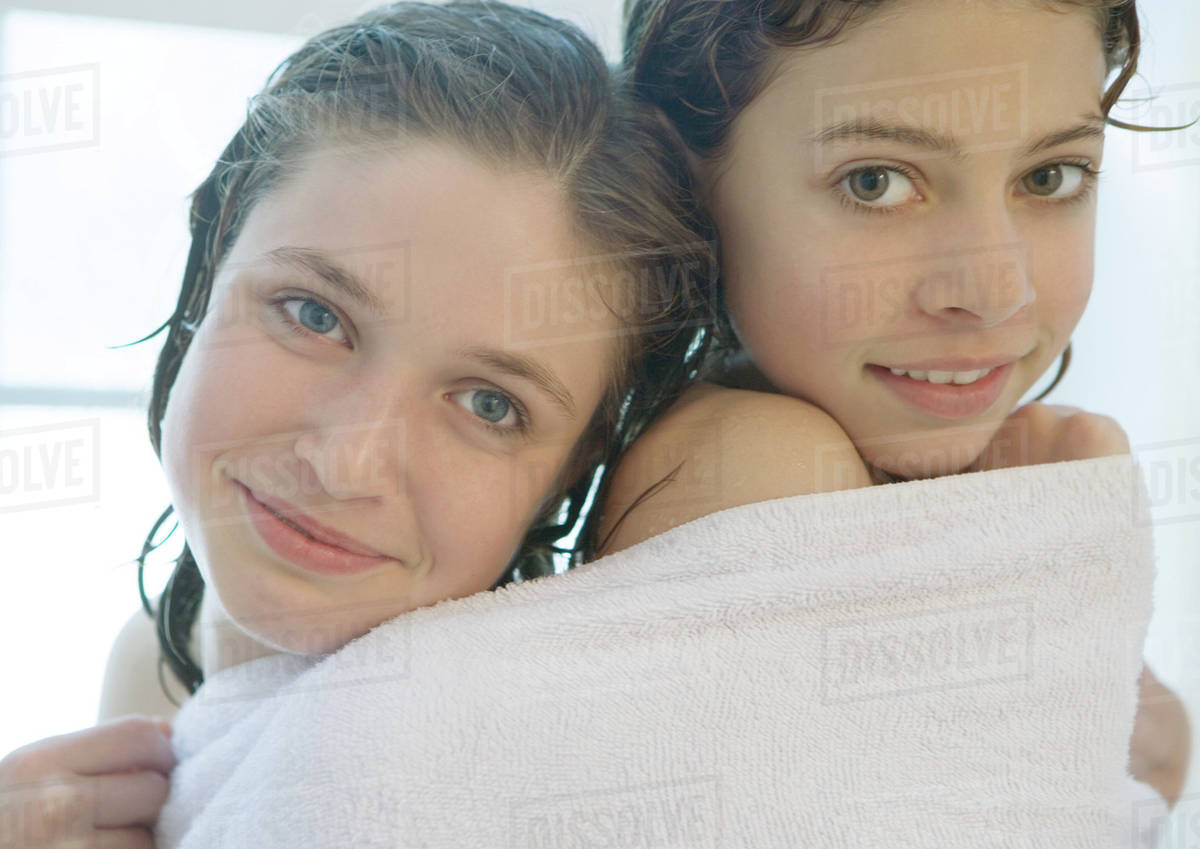 Two preteen girls sharing towel - Stock Photo - Dissolve