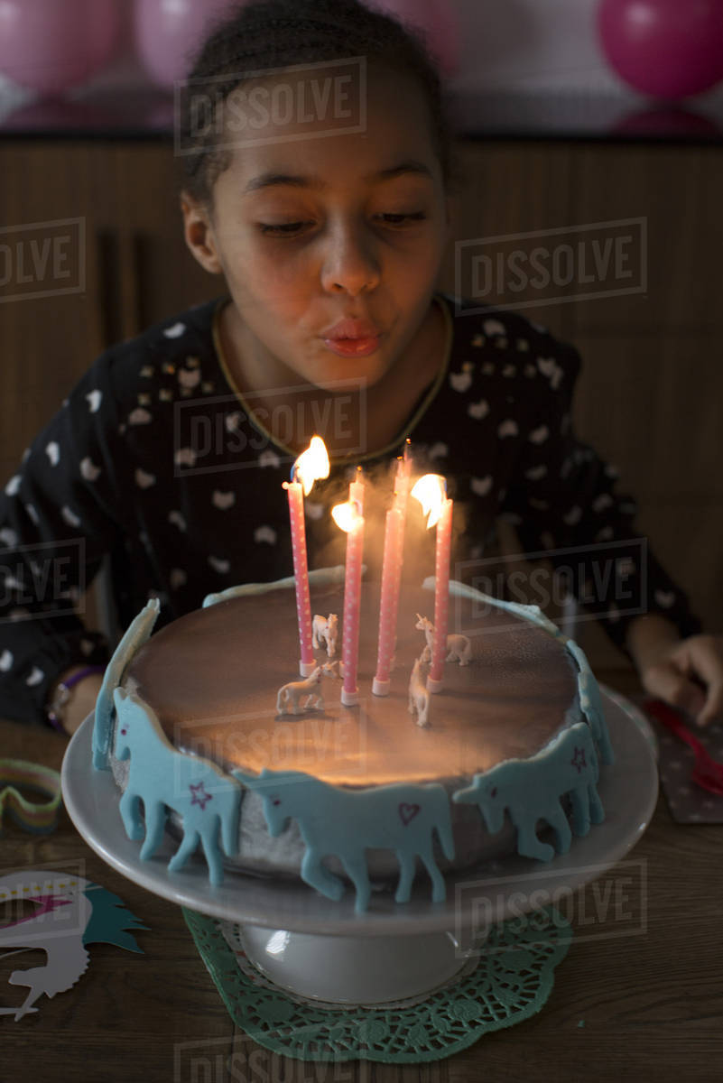 Girl blowing out candles on birthday cake Stock Photo Dissolve