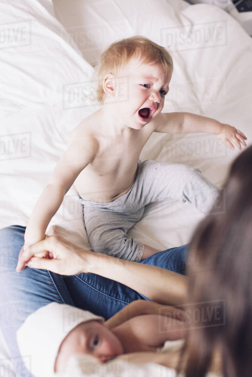 Mother Comforting Crying Child While Breast Feeding Stock Photo