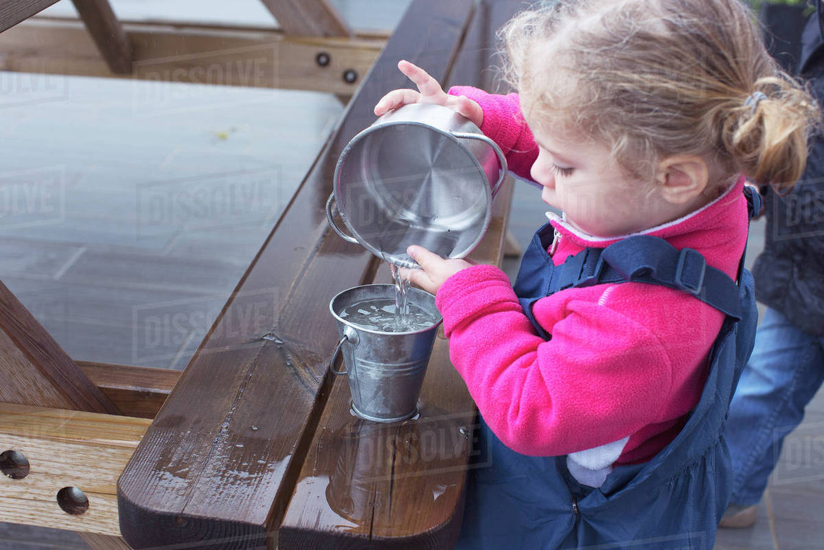 Little girl pouring water from one pail to another Stock Photo Dissolve