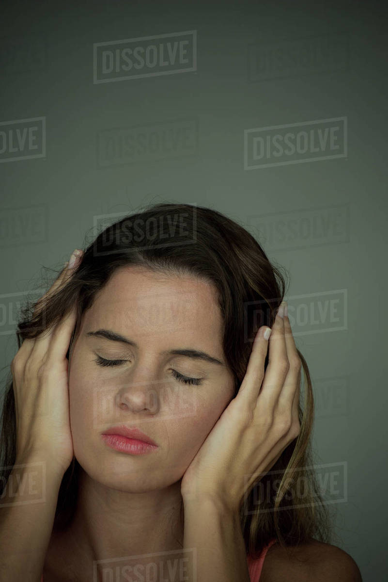 Woman holding hands over ears with eyes closed Stock Photo Dissolve