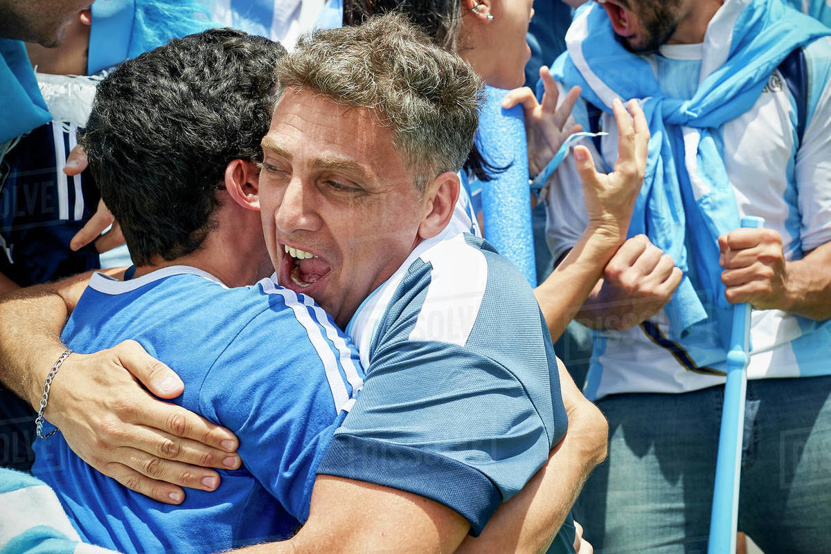 Argentinian football fans embracing at football match Stock Photo