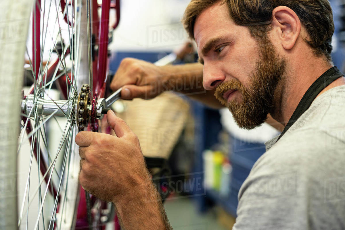 Mechanic repairing bicycle wheel in Stock Photo Dissolve
