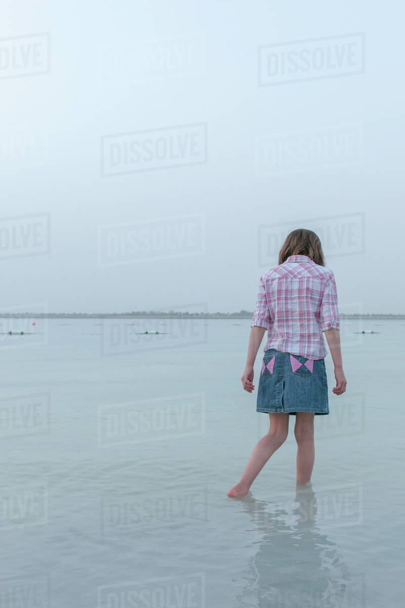 Girl wading in water at the beach Stock Photo Dissolve
