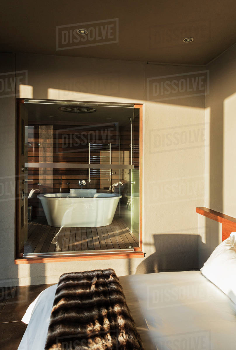 Modern bedroom with glass window to bathroom - Stock Photo - Dissolve
