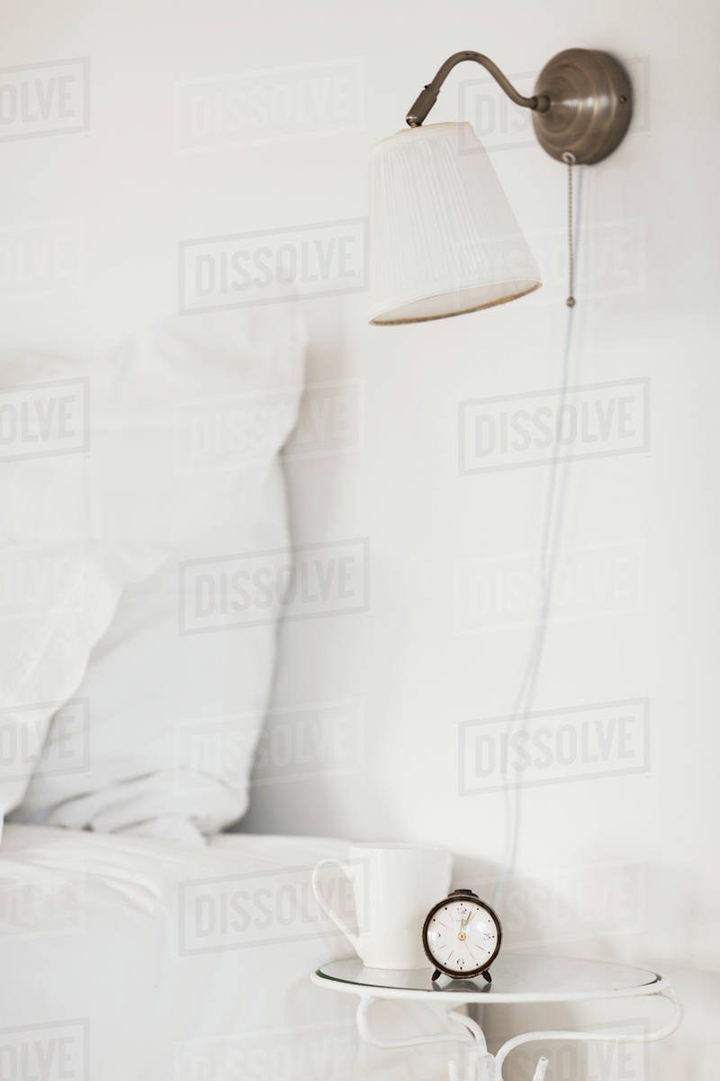Lamp and bedside table in white bedroom Stock Photo Dissolve
