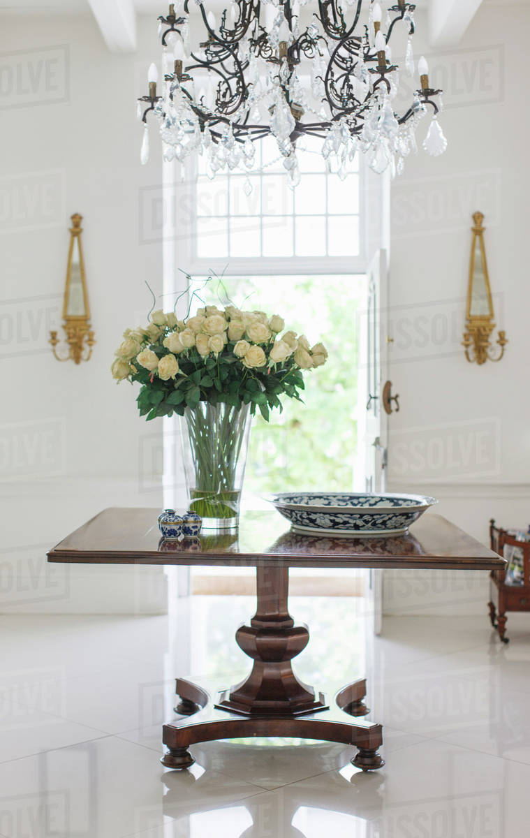 Chandelier Over Bouquet On Table In Luxury Foyer Stock Photo