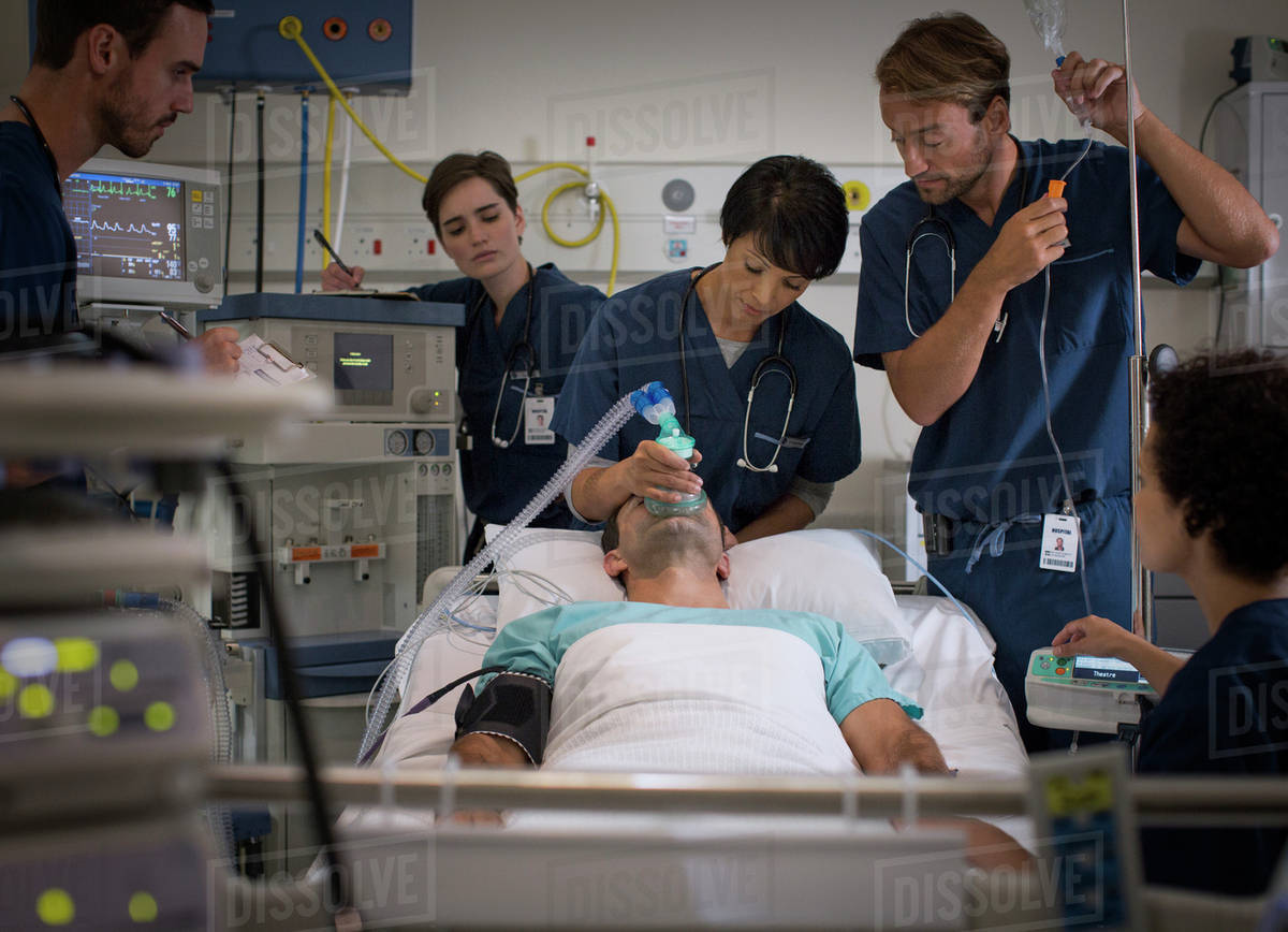 Doctor holding mask over patient's mouth and doctor controlling IV drip in intensive care unit Royalty-free stock photo