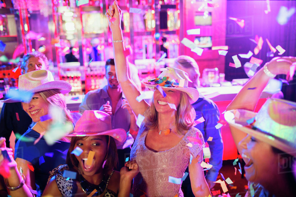Confetti falling on women wearing cowboy hats dancing in nightclub - Royalty -free Stock Photo | Dissolve