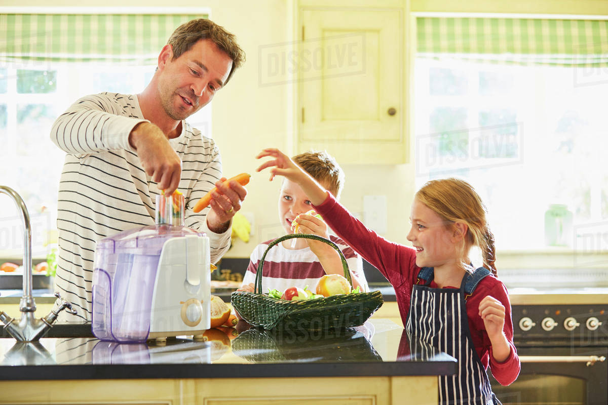 Family juicing vegetables in kitchen Stock Photo Dissolve
