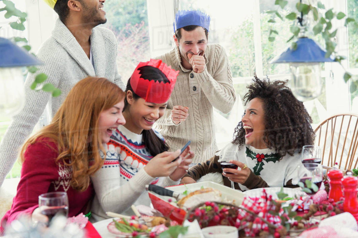 Laughing friends wearing paper crowns at Christmas dinner Royalty-free stock photo