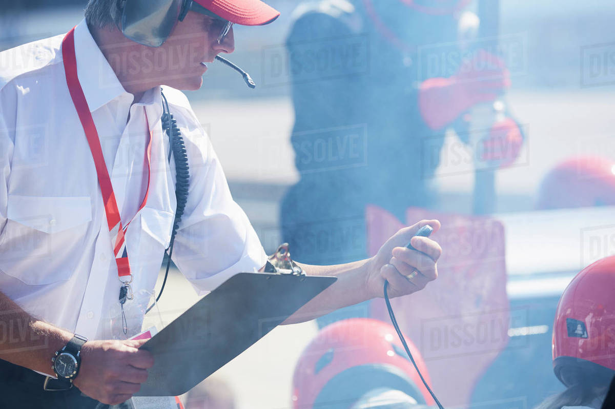 Manager with clipboard and stopwatch timing formula one pit crew practice session Royalty-free stock photo