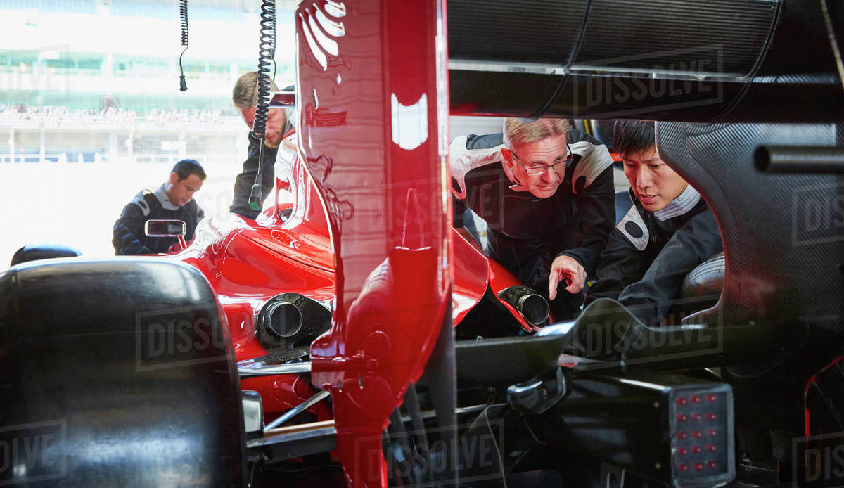 Pit crew mechanics examining race car in repair garage Royalty-free stock photo