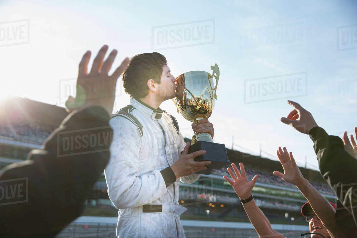 Formula one racing team cheering around driver kissing trophy, celebrating victory Royalty-free stock photo