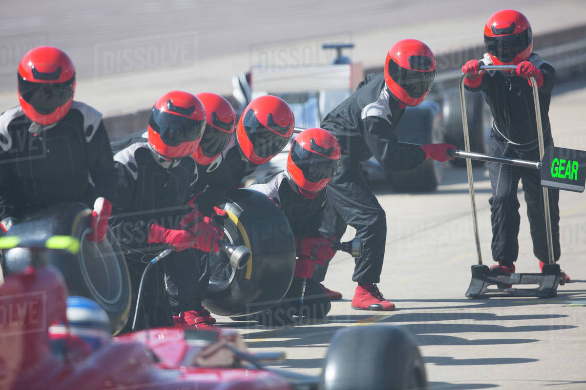 Pit crew with tires ready for nearing formula one race car in pit lane Royalty-free stock photo