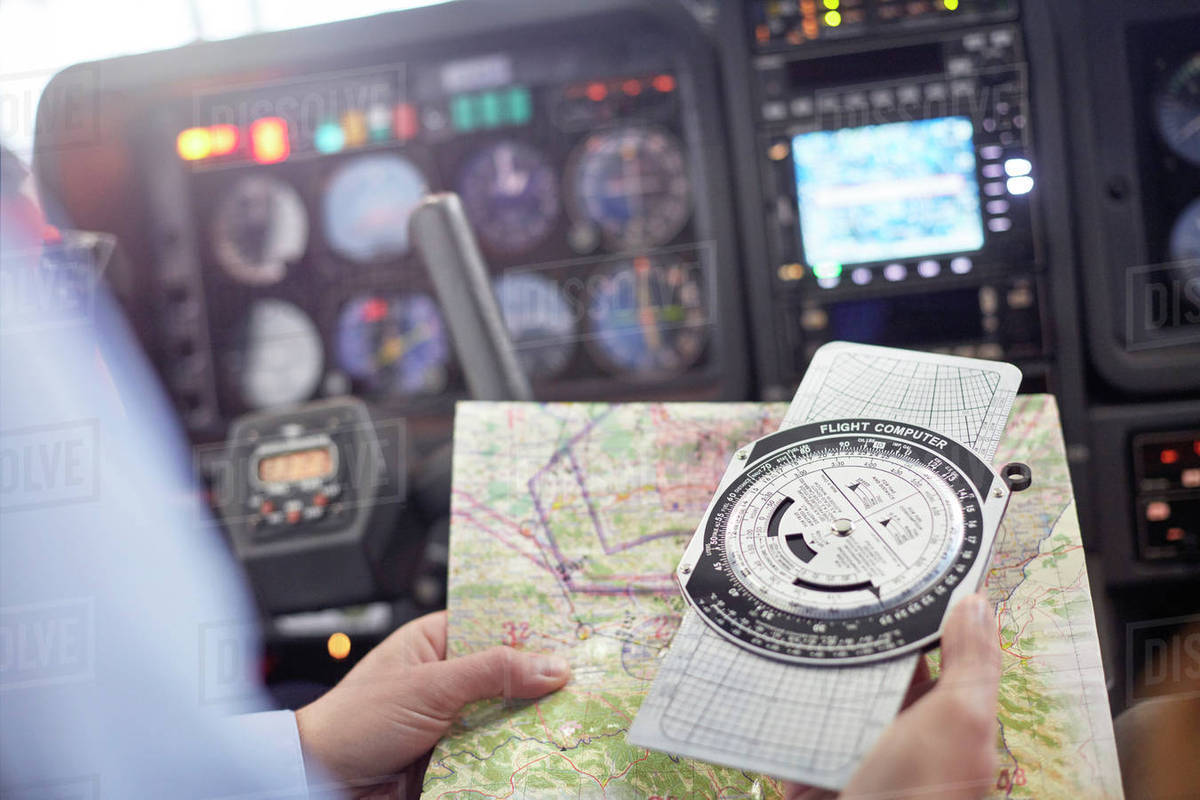 Pilot checking navigational map and compass instrument in airplane