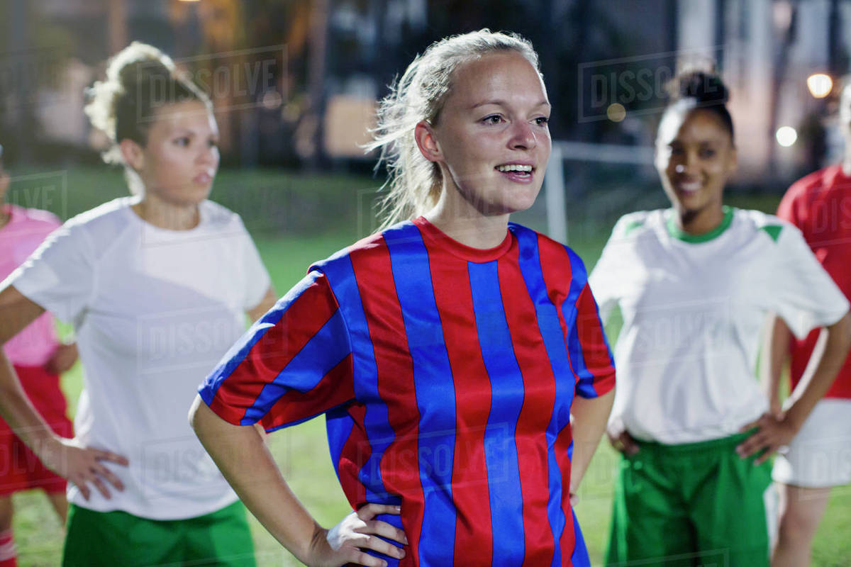 Confident young female soccer players resting with hands on hips on