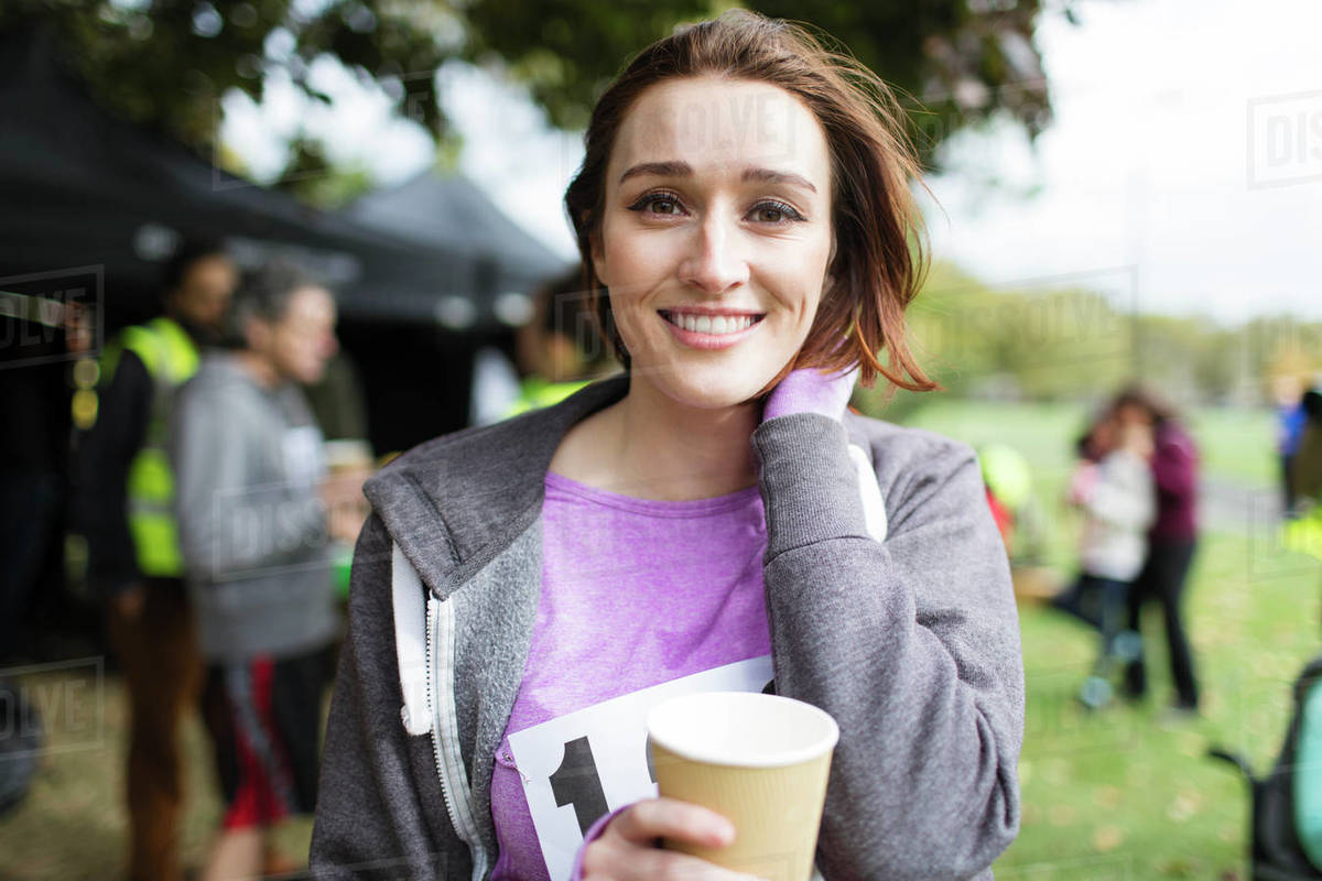 Portrait smiling female marathon runner drinking water in park Stock Photo Dissolve