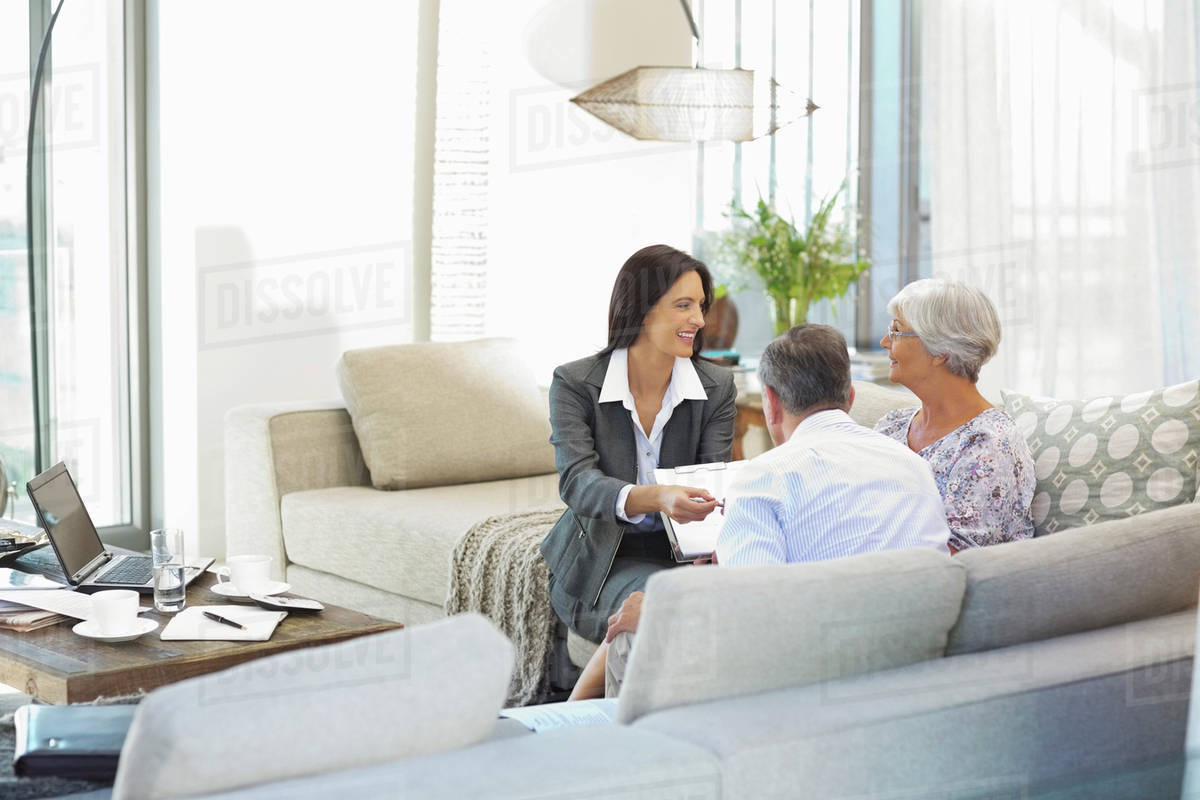 Financial advisor talking to couple on sofa Stock Photo Dissolve