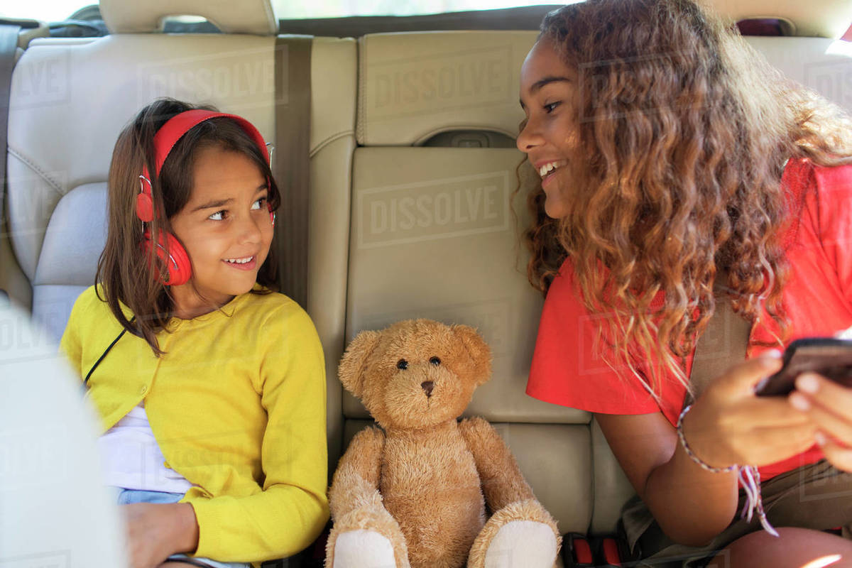 Sisters and teddy bear riding in back set of car Royalty-free stock photo